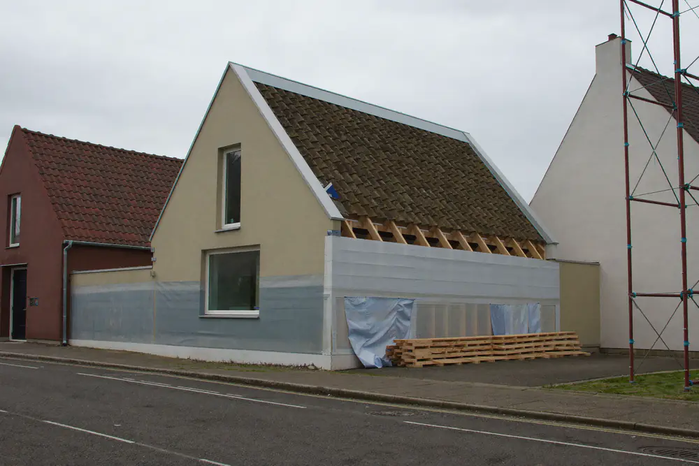 Twee-onder-een-kapwoning met een nokverhoging in aanbouw en een steiger aan de zijkant