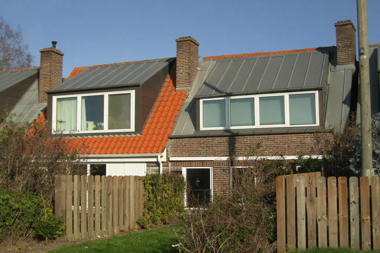 Twee naast elkaar gelegen woningen met brede dakkapellen met zinken dak en witte kozijnen op het achterdakvlak